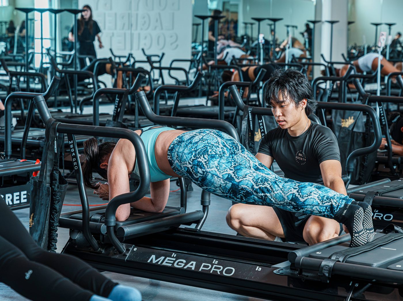 A trainer kneeling to spot a member's plank form